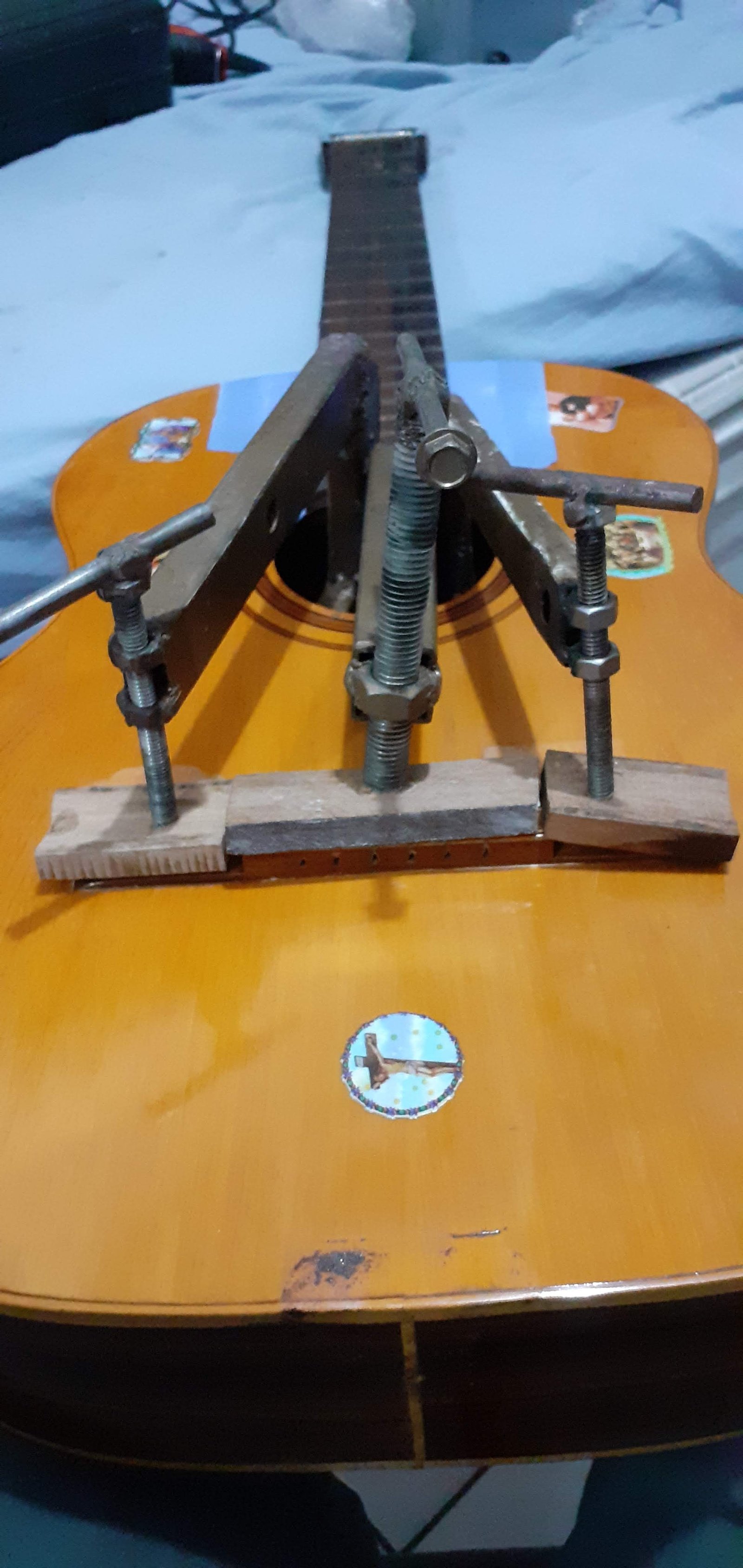 Cavalete do violão sendo colado com grampo especial passado pela boca do instrumento